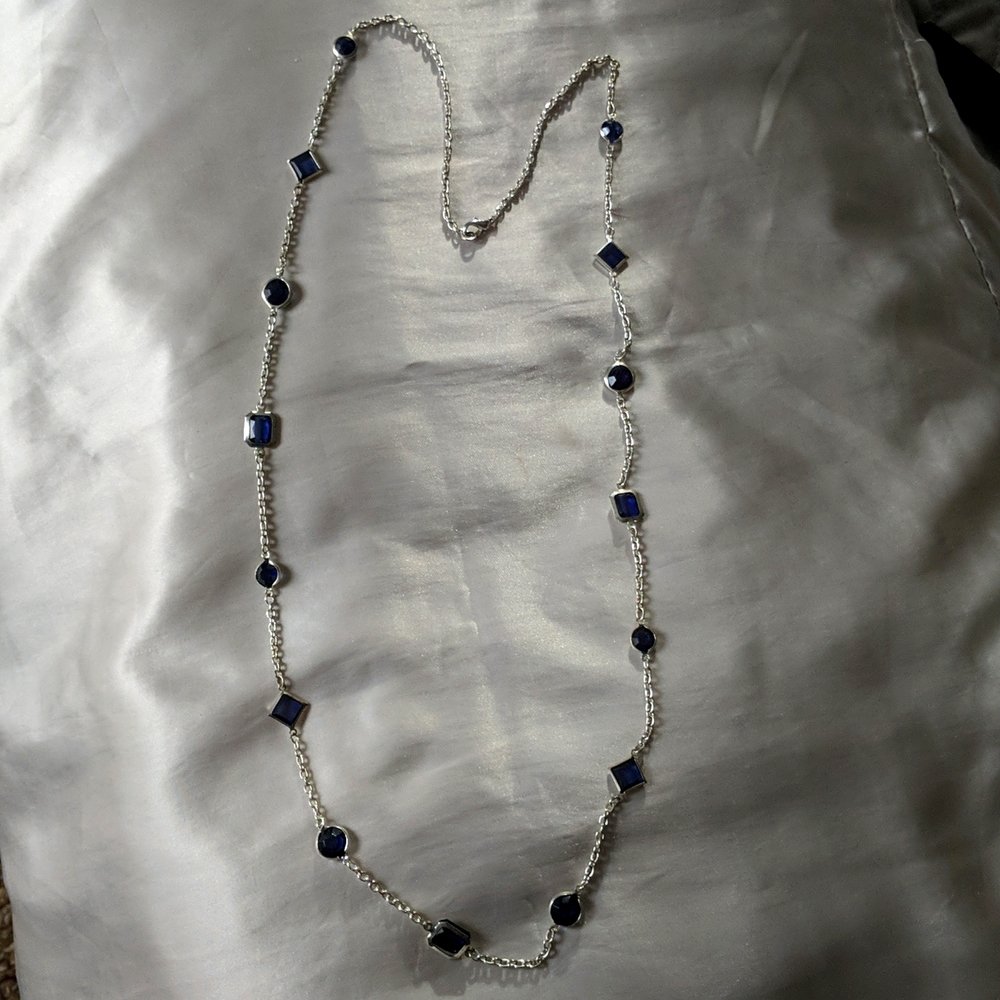 Long silver necklace with blue crystals.